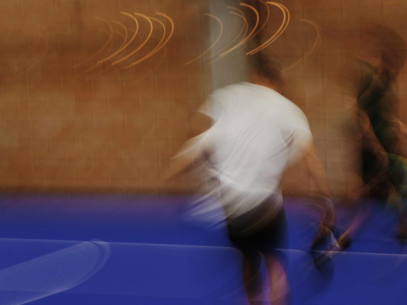Dues persones en moviment en una pista blava, fotografiades amb desenfocament.