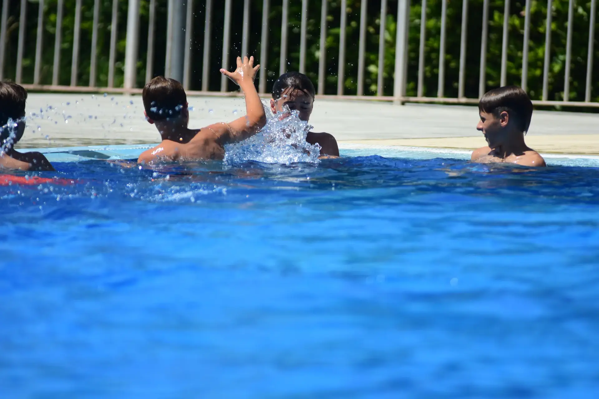 Grup d'infants jugant en una piscina durant una activitat d'estiu.